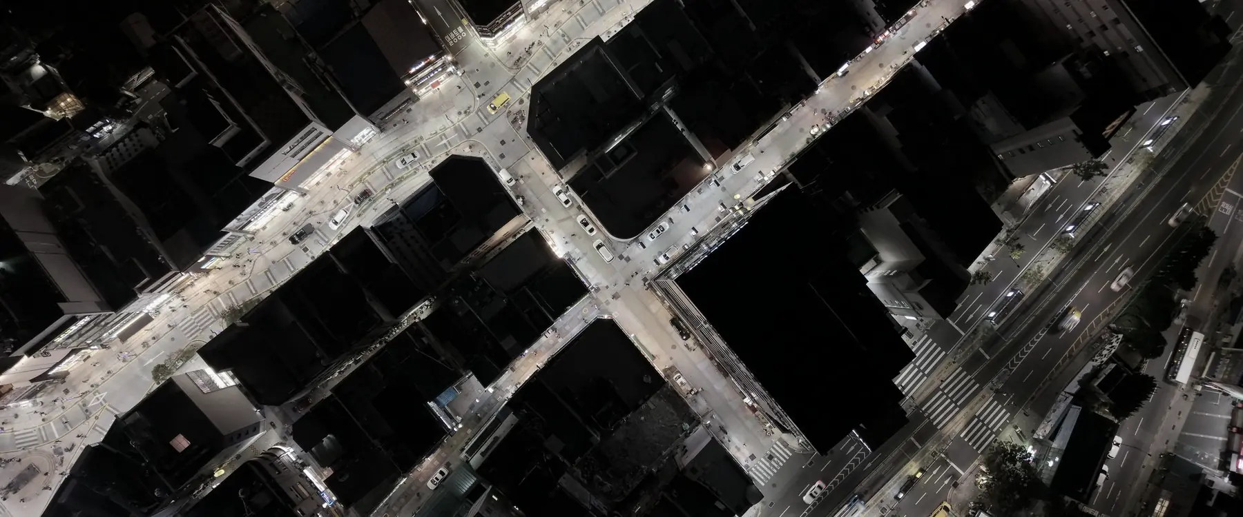 A city street grid seen from above at night, roads picked out by streetlight