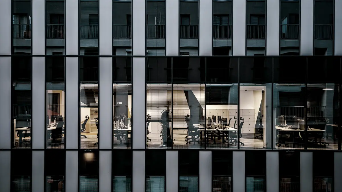 The lit floors of an office building at night, seen as a grid of windows