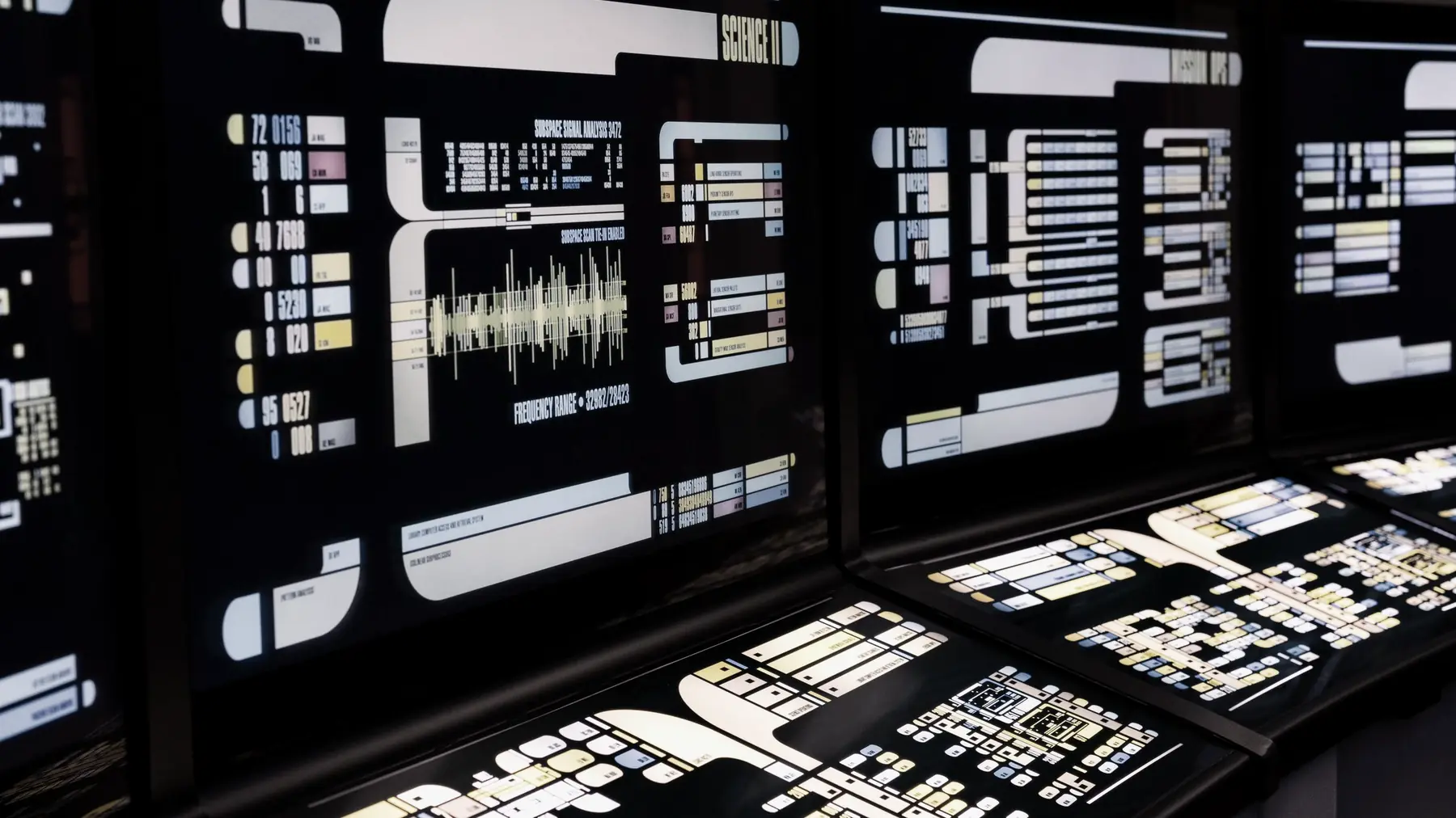 Rows of unattended control-room consoles, their panels lit in a darkened room