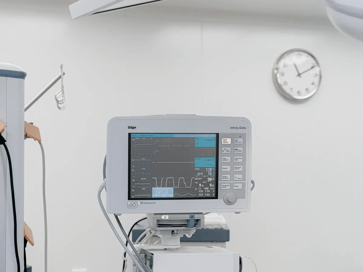 A vital-signs monitor and a wall clock in an otherwise empty clinical room