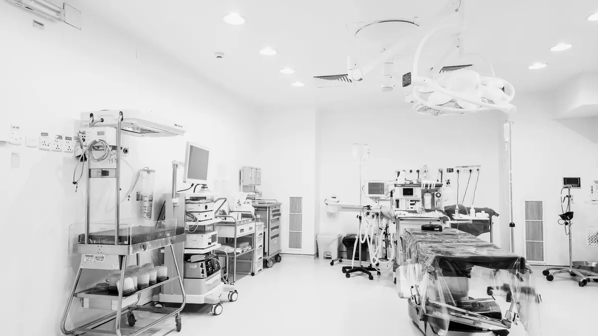 An empty operating room, lights and instrument trolleys in place